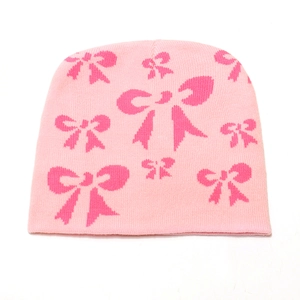 Dettaglio del berretto in maglia rosa con motivi jacquard a fiocco rosa scuro