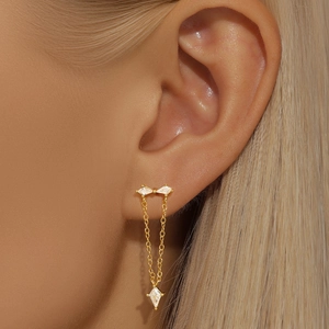 Vue détaillée du piercing d'oreille doré avec losange serti de zircons et chaîne pendante