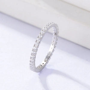 Macro shot of silver eternity ring with clear round cubic zirconia stones on white surface