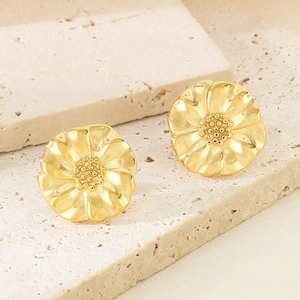 Macro shot of 18K gold floral earrings with textured petals on a stone surface