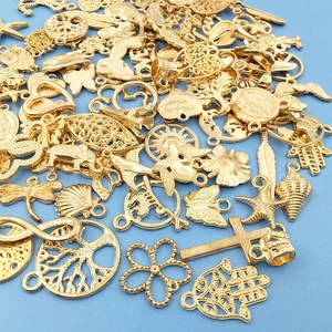 Close-up of assorted gold alloy charms like butterfly and cross on blue background
