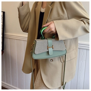 Detail of cross-body box bag with green leather, striped fabric flap and H-shaped buckle