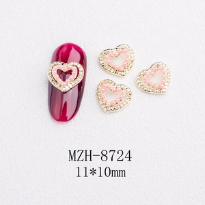 Macro view of 11x10mm pink pearl heart nail charms with gold metal edges and rhinestones