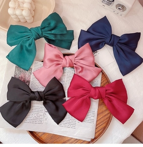 Collection of oversized French satin bow hair clips in multiple vintage colors on a tray