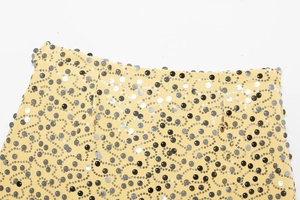 Close-up detail of silver and black sequins on a yellow wrap skirt fabric texture