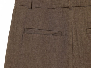 Macro shot of brown trousers featuring waist belt loops and a welt pocket with twill texture