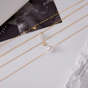 Détail de quatre colliers dorés en acier inoxydable avec perles et pendentifs zircons