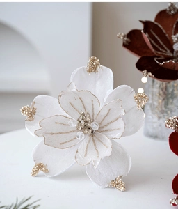 Close-up of white velvet Christmas flower with gold glitter edges and bead center