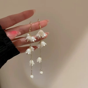 Close-up of lily of the valley earrings with gold long tassels and white pearls