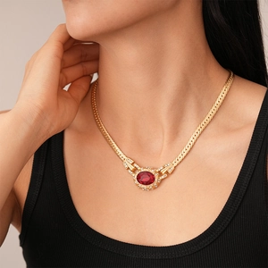Close-up of a vintage gold chain necklace featuring a red oval gemstone and rhinestones