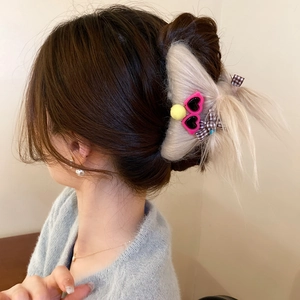 Detail of cream plush monster hair claw with pink sunglasses and plaid bow accessory