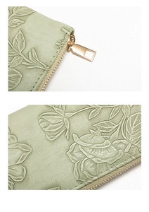Detail of light green floral embossed leather wallet with golden zipper hardware