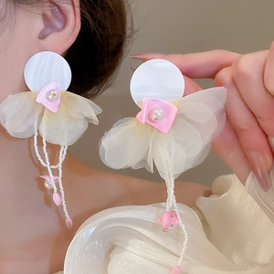 Close-up of oversized floral tassel earrings with organza petals and pearls on model