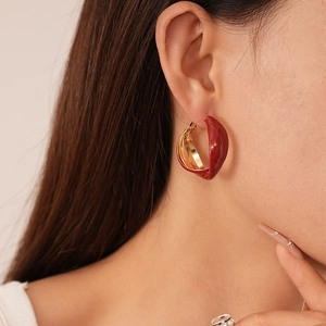 Close-up of vintage red enamel and gold geometric twisted hoop earrings on model