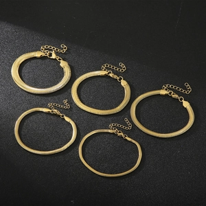 Set of five gold snake bone chain bracelets with lobster clasps on a black background