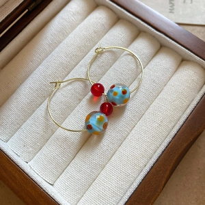 Detail of colorful resin beads on gold hoop earrings in a wooden jewelry gift box