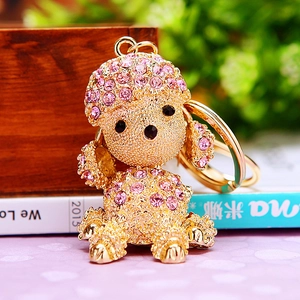 Close-up of golden metal puppy keychain with pink rhinestones on a decorative desk