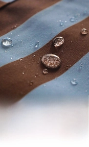 Macro shot of water droplets on waterproof blue and brown striped cotton apron fabric