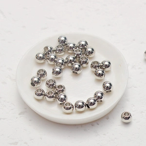 Vue détaillée de perles rondes argentées polies pour bijoux DIY sur céramique blanche
