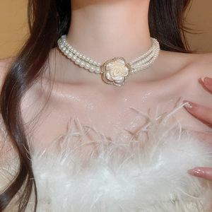 Close-up of elegant double-layer pearl necklace with a diamond-studded shell camellia flower