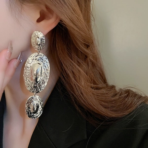 Close-up of hammered silver oval drop earrings showing metallic texture and vintage style