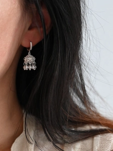 Close-up of silver hollow Jhumka earrings with hanging white pearls on model ear
