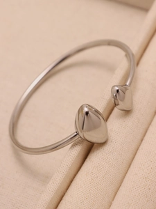 Vue macro d'un bracelet jonc en acier inoxydable argenté poli avec embouts en goutte