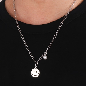 Detail of silver paperclip chain necklace with hollow smiley face pendant and pearl