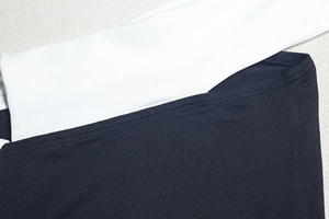 Dettaglio delle cuciture a contrasto su un mini abito bianco e nero con spalle scoperte