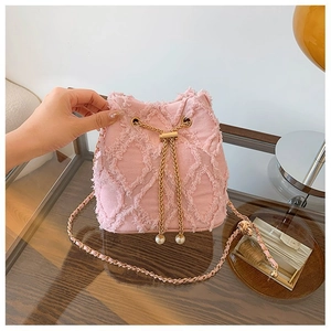 Detail of pink denim bucket bag with diamond quilting, gold chain and pearl drawstring