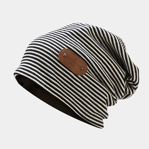 Detail of vintage striped knit beanie featuring a brown leather brand tag and metal rivets