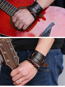 Close-up of men's wide brown leather bracelet and beaded wristbands on a guitar player