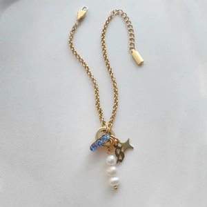 Gold titanium steel charm bracelet featuring pearls, blue crystals, and a star pendant