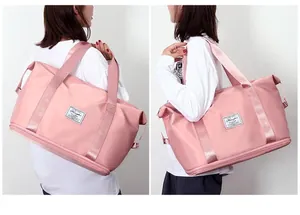Grande borsa da viaggio rosa in nylon impermeabile indossata a tracolla