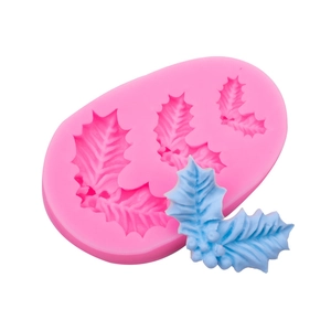 Pink silicone holly leaf mold with blue finished berry craft on white background
