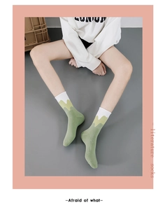 Detail of green knitted cotton mid-calf socks with white wavy pattern on the cuff