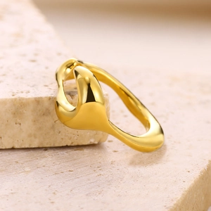 Detailed close-up of a golden irregular wavy open ring on a travertine stone surface