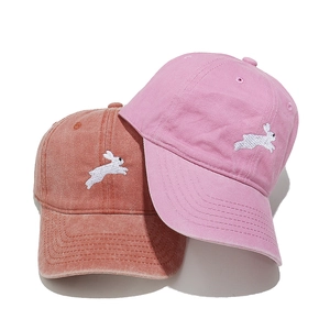 Close-up of cute rabbit embroidery on washed cotton baseball caps in terracotta and pink