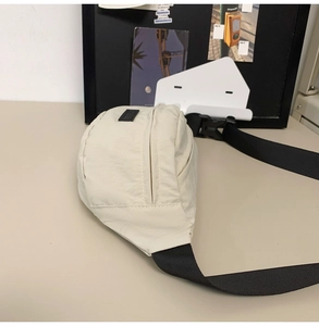 Detailed side view of off-white minimalist chest bag featuring black plastic buckle and strap
