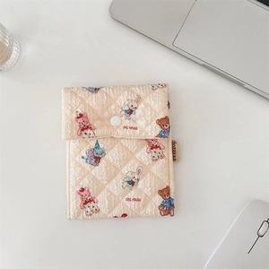 Close-up of quilted beige storage pouch featuring cute cartoon animal prints and button closure