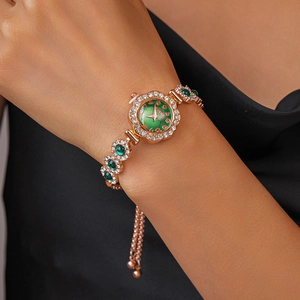 Detail of rose gold watch bracelet with emerald gemstones and white zircon on female wrist
