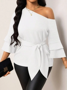 Close-up of white off-shoulder top with ruffled sleeves and textured waist belt