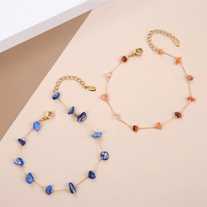 Golden stainless steel chain bracelets with blue and orange crushed stones on modern background