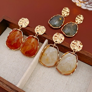 Detail of vintage irregular round earrings with amber and cream resin stones in a wooden box
