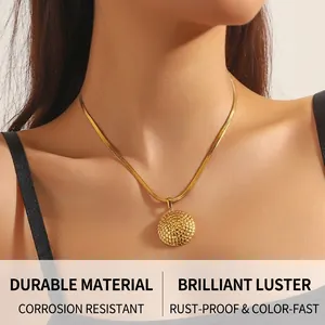 Detail of a gold-plated spiral disc pendant necklace on a snake chain for women