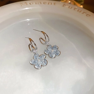 Macro view of blue crystal flower earrings with pearls and rhinestones on ceramic dish