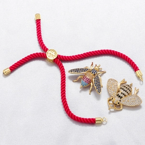 Detail of bee charms with zircon inlays and adjustable red woven bracelet cord