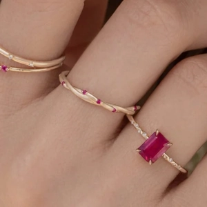 Close-up of rose gold twisted rings featuring rectangular ruby and pink stones
