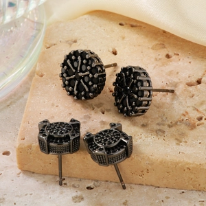 Geometric black zircon stud earrings in round and square shapes on stone pedestal