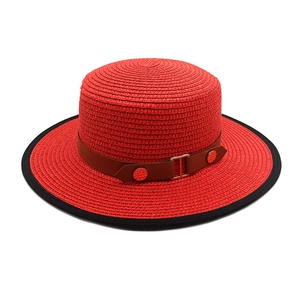 Close-up of red straw boater hat with brown leather belt buckle and black trim